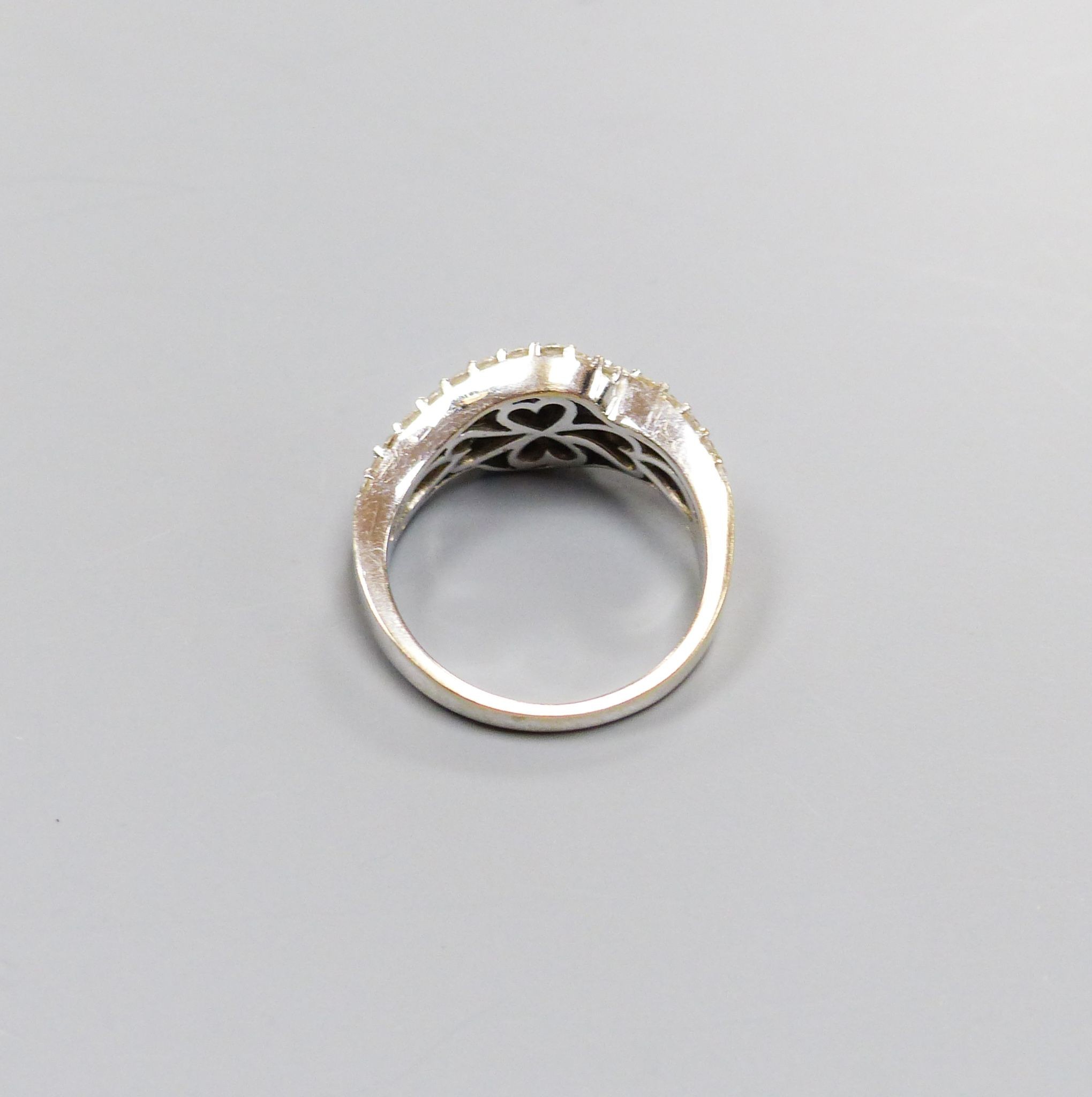 A modern 750 white metal, baguette and round cut diamond set two row crossover ring, size M/N, gross 5.4 grams, (one stone missing).